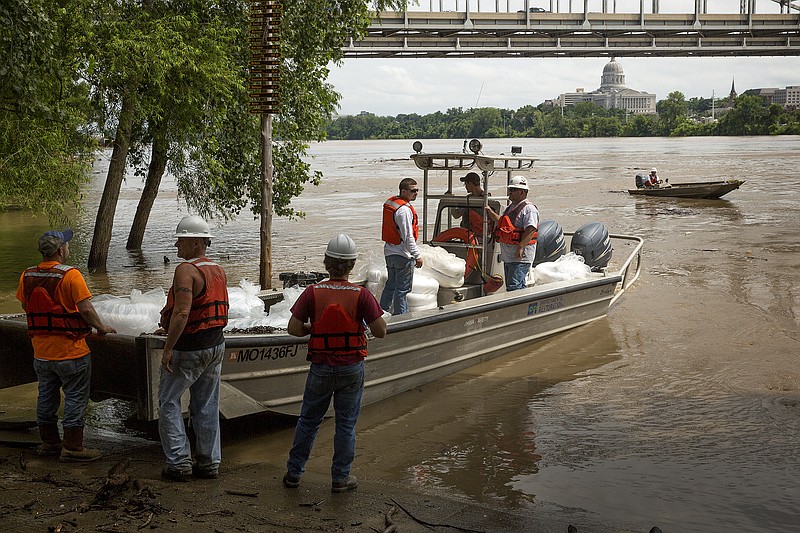 Workers with Environmental Restoration, LLC load boats Friday into the Missouri River at Noren Access to begin the process of moving a sand dredge that flipped.