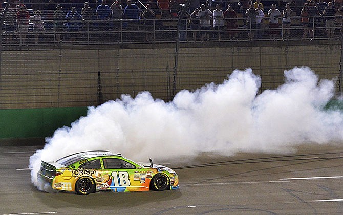 Kyle Busch does a burnout after his victory in the NASCAR Sprint Cup series auto race at Kentucky Speedway in Sparta, Ky., Saturday, July 11, 2015. 