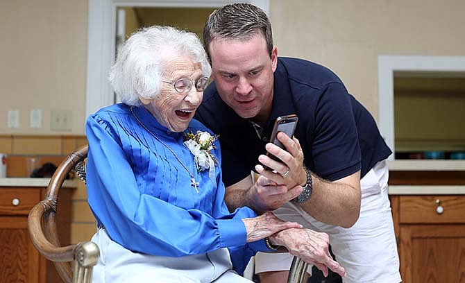 Mildred Landwehr looks at pictures of Matt Landwehr's two-week-old daughter Saturday at her 100th birthday celebration in Jefferson City. Family members and friends waited in line to speak with Mildred, who was described as an "iconic" member of the family and community.