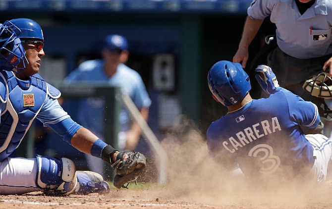 Toronto Blue Jays' Ezequiel Carrera (3) beats the tag by Kansas City Royals catcher Salvador Perez, left, during the sixth inning of a baseball game at Kauffman Stadium in Kansas City, Mo., Sunday, July 12, 2015. Carrera was safe on the play. The Blue Jays scored eight runs in the inning. 