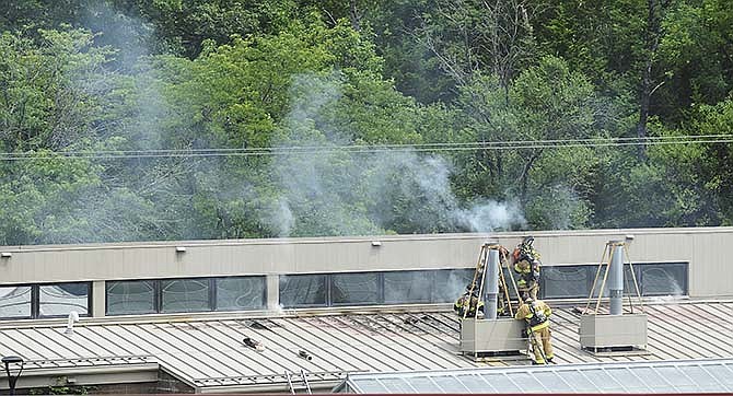 Jefferson City firefighters use a heavy-duty circular saw to cut through the metal roof at Dickinson Research Center on the Lincoln University campus.