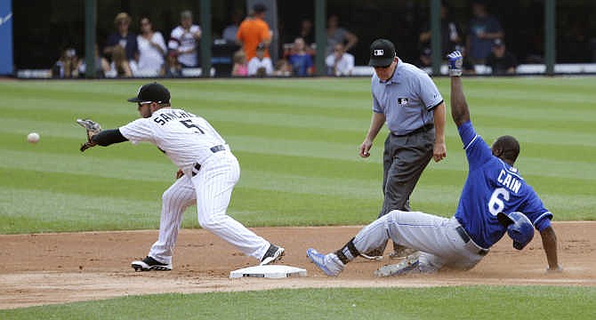 Kansas City Royals' Lorenzo Cain, right, slides safely into second after hitting an RBI double, scoring Alcides Escobar, as Chicago White Sox second baseman Carlos Sanchez takes the throw from left fielder Melky Cabrera, during the first inning of a baseball game Friday, July 17, 2015, in Chicago. Watching the plays is second base umpire Jerry Meals.