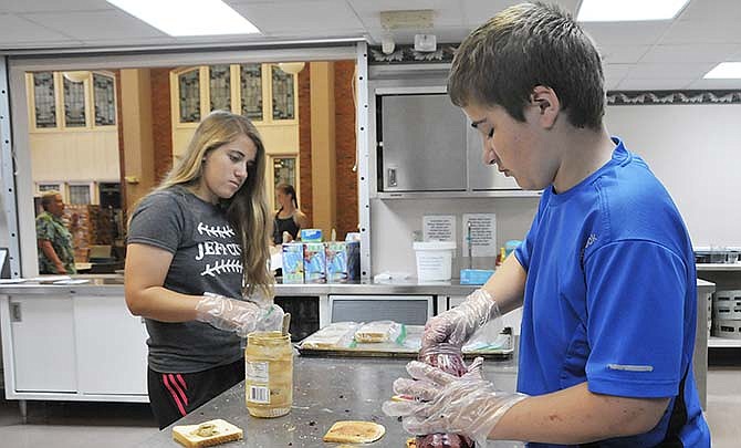 Siblings Drew, 13,
right, and Lauren Neubauer,
15, make sandwiches
that will be delivered to
Jefferson City area youngsters who may not
otherwise have anything to
eat. Throughout the course
of the week, volunteers
made and gave out approximately
600 brown bag
lunches.