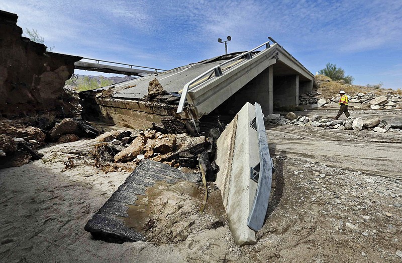 A worker walks near a washed-out bridge near the town of Desert Center, along Interstate 10 in Southern California, on Monday. All traffic along one of the major highways connecting California and Arizona was blocked indefinitely when the bridge over a desert wash collapsed during a major storm, and the roadway in the opposite direction sustained severe damage.