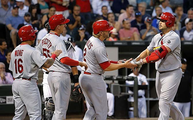 St. Louis Cardinals' Matt Holliday, right, is greeted at home by Kolten Wong (16), Steven Piscotty (55) and Mark Reynolds after the quartet scored on Holiday's grand slam off Chicago White Sox starting pitcher Carlos Rodon, during the fourth inning of an interleague baseball game Tuesday, July 21, 2015, in Chicago.