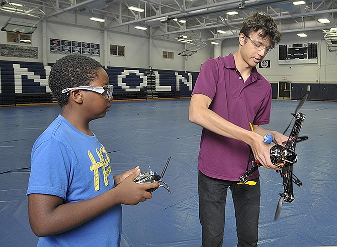 Adam Eaton, right, shows Christian Flowers, 12, how to calibrate the drone before flying it in the Jason Gym on Thursday. This week's drone camp was created by Lincoln University Cooperative Extension and the Paula J. Carter Center.