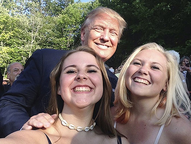 Republican presidential hopeful Donald Trump poses for a photo with Emma Nozell, left, and her sister Addy Nozell in Laconia, New Hampshire. The teenagers from Merrimack, New Hampshire, are attempting to take photos with every presidential candidate campaigning in the state.