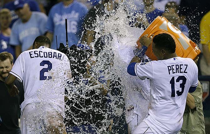 Kansas City Royals' Salvador Perez (13) dumps water on teammates Alcides Escobar (2) and Paulo Orlando following a baseball game against the Houston Astros at Kauffman Stadium in Kansas City, Mo., Saturday, July 25, 2015. Escobar drove in Orlando for the game winning run. The Royals defeated the Astros 2-1 in ten innings. 