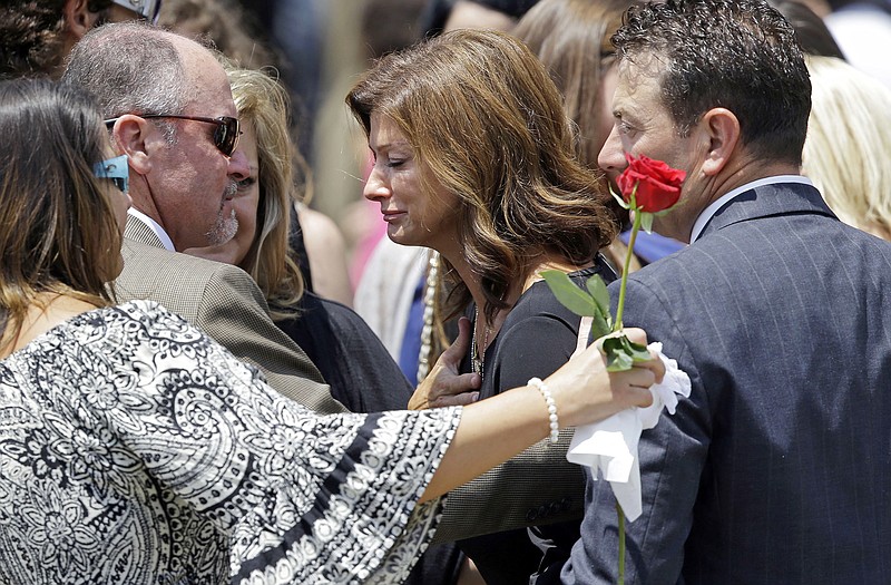 Dondie LeBlanc Breaux, mother of Mayci Breaux, center, and Kevin Breaux, right, father of Mayci, are comforted outside the Church of the Assumption, after her Monday funeral in Franklin, La. She was one of two people killed in Thursday's movie theater shooting in Lafayette, La.  