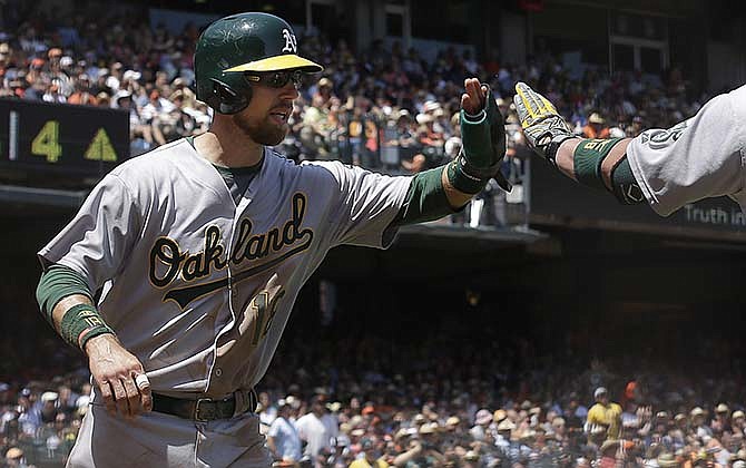 Oakland Athletics' Ben Zobrist is congratulated by a teammate after scoring against the Giants in San Francisco, Sunday, July 26, 2015. The Kansas City Royals acquired the versatile Zobrist from Oakland as part of a deal on Tuesday.