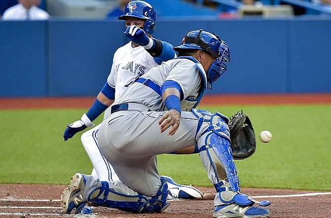 Toronto Blue Jays shortstop Troy Tulowitzki, back, scores at home plate past Kansas City Royals catcher Perez Salvador during the first inning of a baseball game, Thursday, July 30, 2015 in Toronto. (Nathan Denette/The Canadian Press via AP)