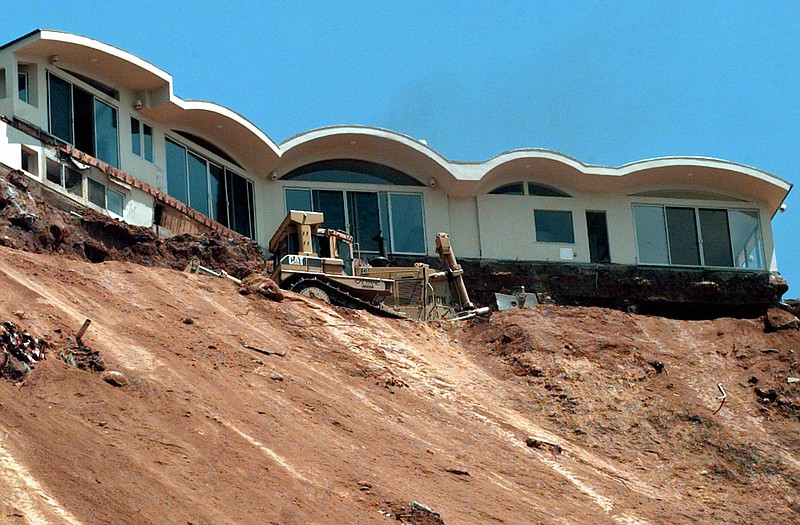 A Caltrans bulldozer terraces a sliding hillside below the condemned home above Pacific Coast Highway near Las Flores Canyon Road in Malibu, California. 