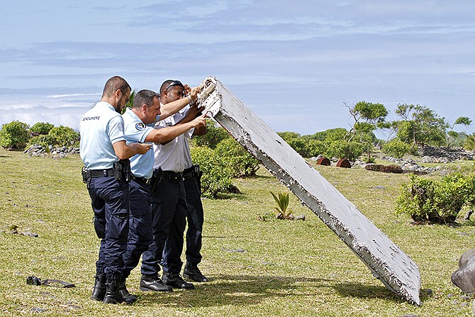 French police officers inspect a piece of debris Wednesday from a plane in Saint-Andre, Reunion Island. Air safety investigators, one of them a Boeing investigator, have identified the component as a "flaperon" from the trailing edge of a Boeing 777 wing, a U.S. official said. Flight 370, which disappeared March 8, 2014, with 239 people on board, is the only 777 known to be missing. 