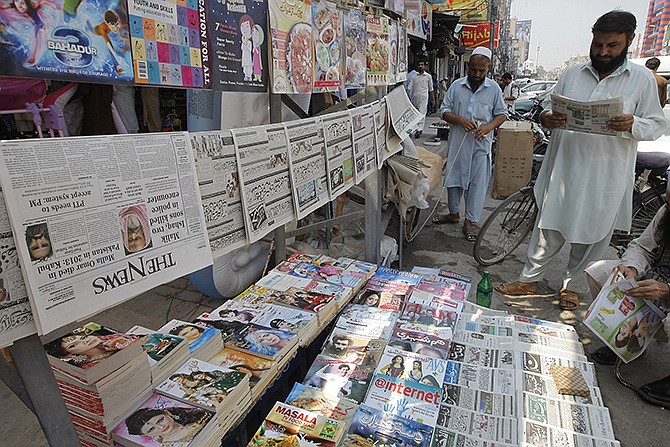 A man reads a newspaper at a news stand Thursday where local newspapers are displayed carrying headlines about the death of Taliban leader Mullah Mohammad Omar, in Peshawar, Pakistan. Afghanistan's Taliban confirmed the death of Mullah Omar, who led the group's self-styled Islamic emirate in the 1990s, sheltered al-Qaida through the 9/11 attacks and led a 14-year insurgency against U.S. and NATO troops. 