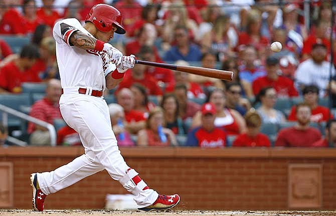 St. Louis Cardinals' Kolten Wong hits into a fielder's choice, driving in Matt Carpenter during the first inning of a baseball game against the Colorado Rockies, Thursday, July 30, 2015, in St. Louis.