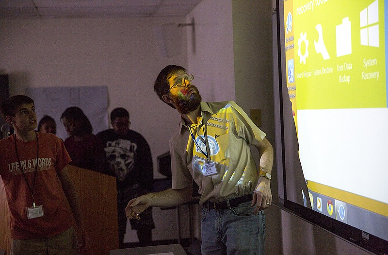 Program director Dr. David Heise helps set up a group's presentation Thursday during his classes final show for parents. Heise taught a weeklong course combining math and music to create synthesized sounds using complex coding.  