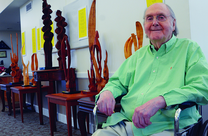 After his 99th birthday celebration at Heisinger Home, E. John Knapp poses with some of the two dozen pieces of art - both painting and sculpture - that are part of an exhibit he currently has at the retirement home. 