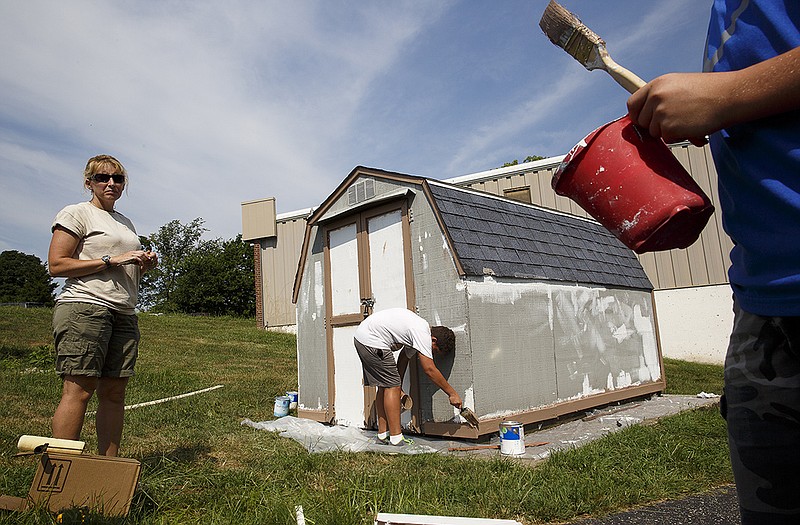 Boy Scouts Tanner Nappier, center, and Connor Hull, right, do touch-up work on the trim of a shed at the Salvation Army Headquarters on Jefferson Street under the supervision of the project's supervisor, Angela Hull. The project will count toward the scouts' Citizenship in the Community merit badge.