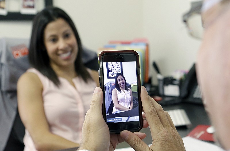 Lauren Simo, left, answers questions during a weekly forum streamed via Periscope on the smartphone of Fish Consulting owner Tony Srebnik, at the company's offices in Hollywood, Florida. Marketing successes with Facebook, Twitter, Pinterest and Instagram have encouraged companies to try streaming apps like Periscope and Meerkat. 
