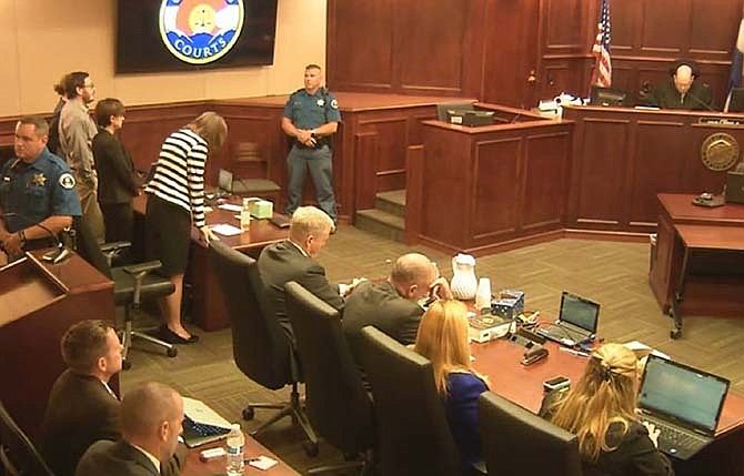 In this image made from Colorado Judicial Department video, Defense Attorney Tamara Brady, at left in stripped suit, leans into the defense table as Judge Carlos A. Samour, Jr., top right, reads the jury's sentencing verdict in the Colorado theater shooting trial in Centennial, Colo., Friday, Aug. 7, 2015. Defendant James Holmes, top left in tan shirt, looks on. Holmes will be sentenced to life in prison without parole after a jury failed to agree on whether he should get the death penalty. 