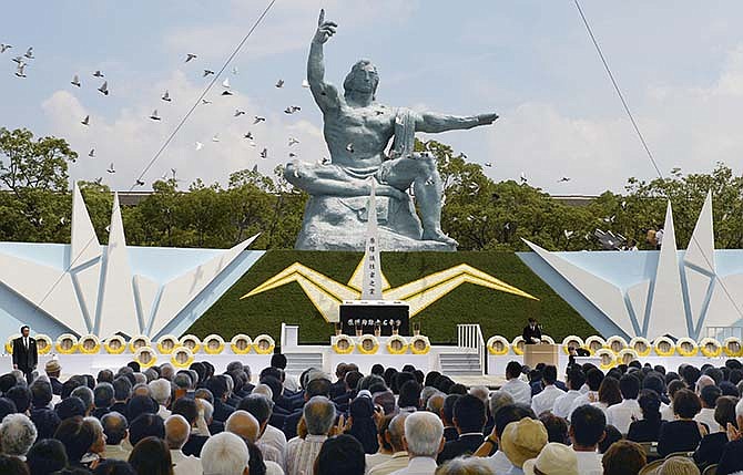 Doves fly over the Statue of Peace during a ceremony at Nagasaki Peace Park in Nagasaki, southern Japan Sunday, Aug. 9, 2015 to mark the 70th anniversary of the world's second atomic bomb attack. The atomic bomb attack on this city that left more than 70,000 dead and hastened the end of World War II exactly 70 years ago. (Kyodo Photo via AP)
