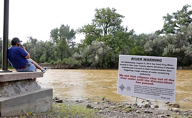 A warning sign from the city is displayed in front of the Animas River as orange sludge from a mine spill upstream flows past Berg Park in Farmington, N.M., Saturday, Aug. 8, 2015. About 1 million gallons of wastewater from Colorado's Gold King Mine began spilling into the Animas River on Wednesday when a cleanup crew supervised by the Environmental Protection Agency accidentally breached a debris dam that had formed inside the mine. The mine has been inactive since 1923. (Alexa Rogals/The Daily Times via AP)