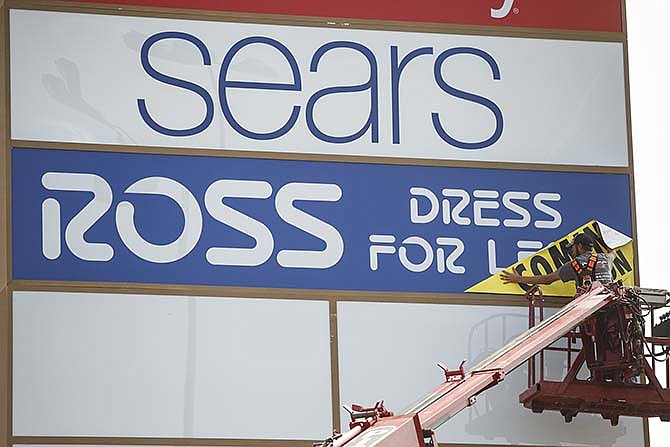 A worker installs a "Coming Soon" banner on the Ross sign that is part of the newly installed Capital Mall
sign next to the Hardee's parking lot on Country Club Drive in Jefferson City.