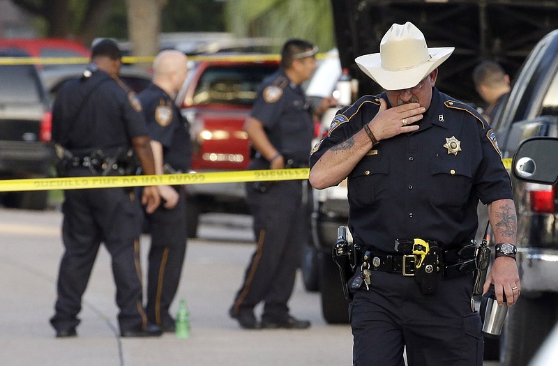 Harris County Sheriff's Department Sgt. D.J. Hilborn, right, walks away from the scene of a multiple shooting Sunday in Houston. 