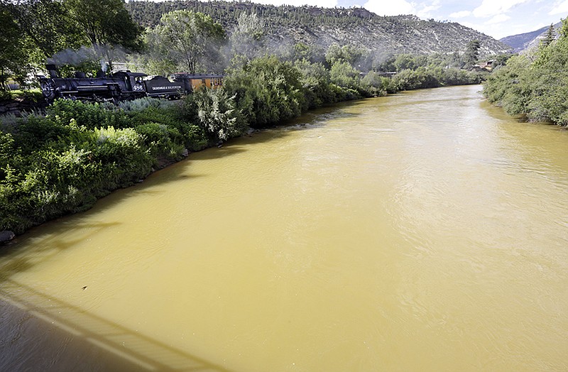 The Animas River is still flowing with toxic waste from the Gold King Mine on Saturday, Aug. 8, 2015, as seen from the 32nd Street Bridge in Durango, Colo., as the Durango & Silverton Narrow Gauge Railroad train passes.