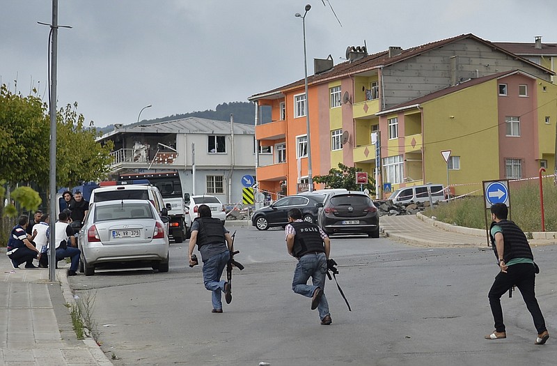 Turkish police officers run for cover during a Monday gunfight near the site of an overnight explosion at a police station in Istanbul's Sultanbeyli neighborhood.