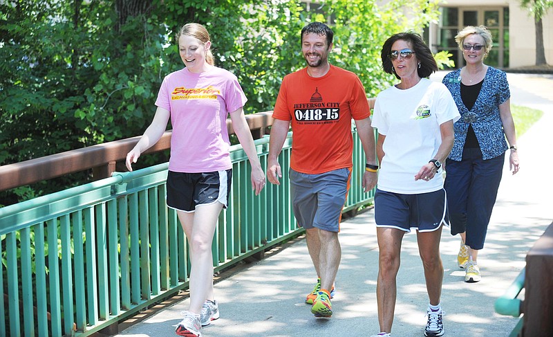 Several employees of JCMG take advantage of the proximity of Jefferson City's Greenway Trail to exercise on breaks and lunch hours. From left, Katie Schad, Jason Kolb, Stephanie Lehmen and Teresa Roe cross the foot bridge on their way to the trail. (August 2015 News Tribune photo)