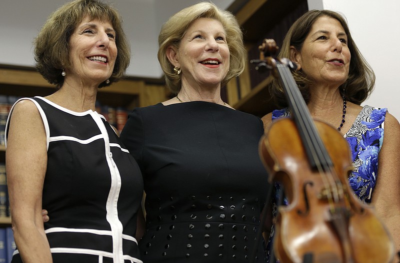 Sisters Jill Totenberg, left, Nina Totenberg, center, and Amy Totenberg pose for pictures with the Ames Stradivarius violin during a news conference in New York, on Thursday. The instrument was stolen from their father, renowned violinist Roman Totenberg, 35 years ago when he left his beloved Stradivarius in his office while greeting well-wishers after a concert in 1980. According to court documents, a woman voluntarily returned the violin to the Totenberg family and told investigators she did not know it was stolen. 