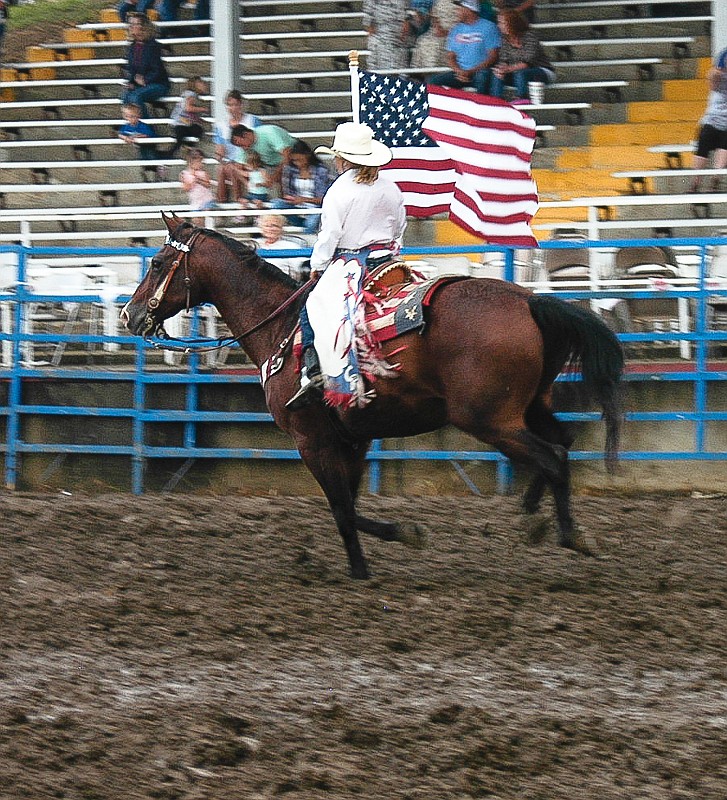 As the national anthem is sang, Old Glory is carried around the arena on horseback at the beginning of the rodeo.