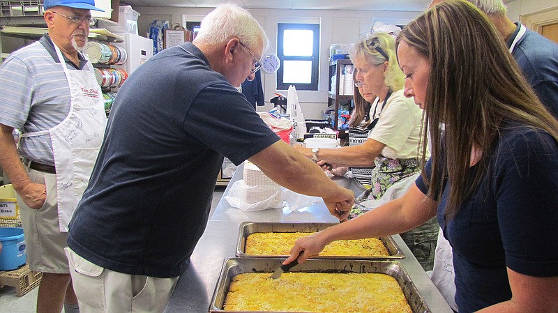 Members of the Fulton Kiwanis Club cut up a dump cake made from white cake mix and pineapple to serve at the Fulton Soup Kitchen in August 2015.