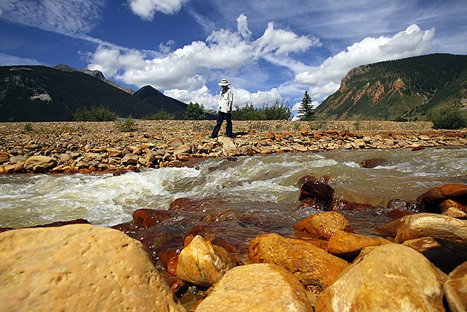 Silverton resident Melanie Bergolc walks Monday along the banks of Cement Creek in Silverton, Colorado. The area is a few miles downstream from the Gold King mine, where a wastewater accident several days earlier allowed yellow water contaminated with heavy metals to pour into the creek that feeds rivers critical to survival on the largest Native American reservation in the United States and across the Southwest. 