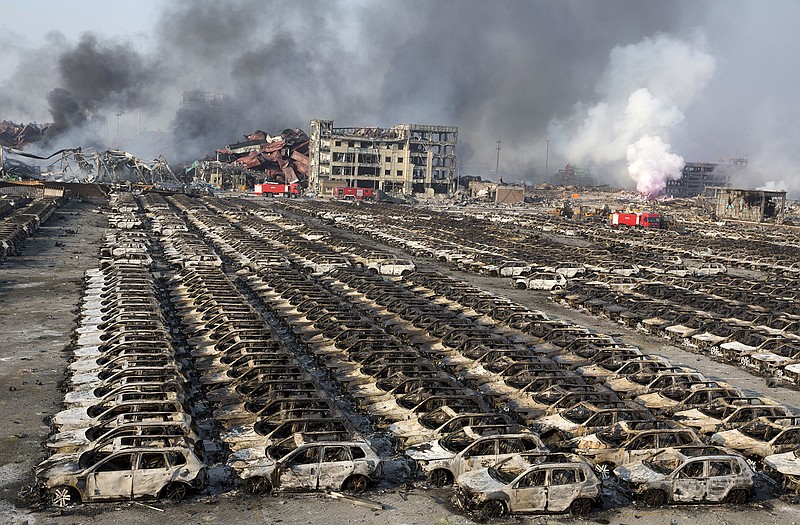 Smoke billows out from the site of an explosion that reduced a parking lot filled with new cars to charred remains at a warehouse in northeastern China's Tianjin municipality.