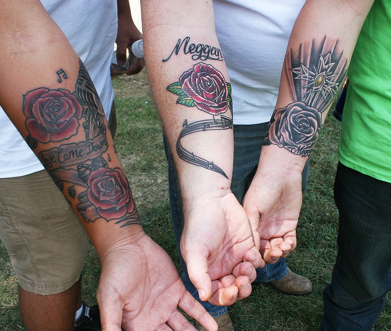 Zeph McDaniel (left), Miriah's brother, shows off a tattoo he had done in his sister's memory at a Saturday fundraiser for the families of the three teenagers who were killed in a car accident on August 1. David Fowler (center) and his son Austin Fowler got tattoos in memory of Meggan Fowler who was also killed in the accident. Matt McDaniel (not shown) went with Austin and Zeph to get tattoos from Eric "Papa Lik" Waldrop, whose niece went to school with Meggan, at The Ink Sling Studio in Jefferson City, Friday.