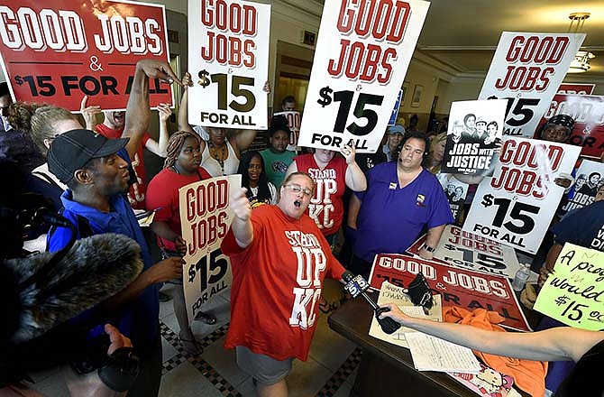 Dana Wittman, of Stand Up KC, center, leads the cheers just outside the council chambers, Thursday, July 16, 2015. Kansas City's minimum wage will rise to $13 an hour over about four and a half years under an ordinance that council members approved Thursday, although there are questions whether it could withstand a legal challenge. (Rich Sugg/The Kansas City Star via AP)