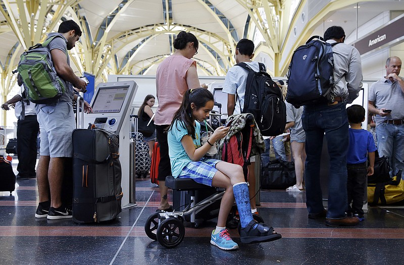 After standing in line for an hour and a half, Alisha Lalani, 10, of Ft. Lauderdale, Fla., looks at her phone as her mother and brother check in for their flight to Miami at Washington's Reagan National Airport.