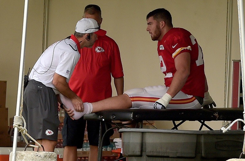 Chiefs tackle Eric Fisher is looked at by a trainer during training camp Monday in St. Joseph.