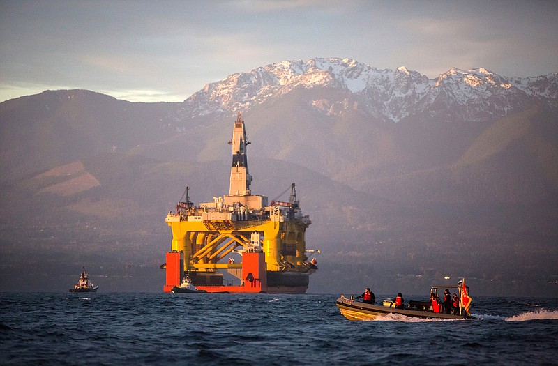 A small boat crosses in front of the Transocean Polar Pioneer, a semi-submersible drilling unit, as it arrives on April 17 in Port Angeles, Washington, aboard a transport ship after traveling across the Pacific before its eventual Arctic destination.