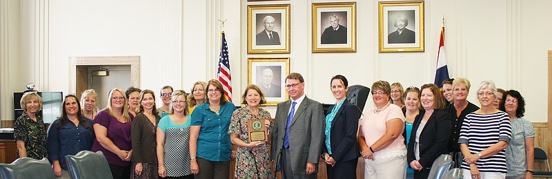 Various groups in the 13th Judicial Circuit Court pose with the Permanency Award they received for the court's hearings in juvenile cases which met timely standards set forth by the Missouri Supreme Court. Missouri Supreme Court Judge Zel Fischer presented the award to presiding Judge Leslie Schneider at a ceremony Tuesday.