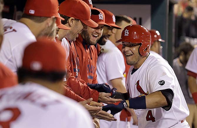 St. Louis Cardinals' Yadier Molina, right, is congratulated by teammates in the dugout after hitting a solo home run during the eighth inning of a baseball game against the San Francisco Giants, Wednesday, Aug. 19, 2015, in St. Louis. 
