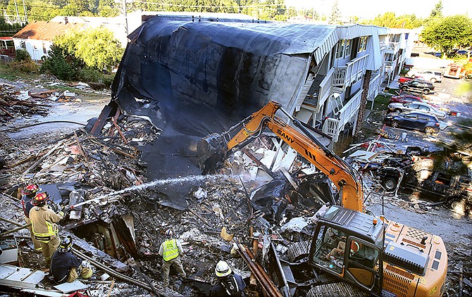 Firefighters hose down the debris field from the collapsed east side of the Bremerton Motel 6 Wednesday morning. A gas explosion leveled the building Tuesday evening. The blast critically injured a gas company worker minutes after the acting hotel manager had evacuated the building due to a gas leak.