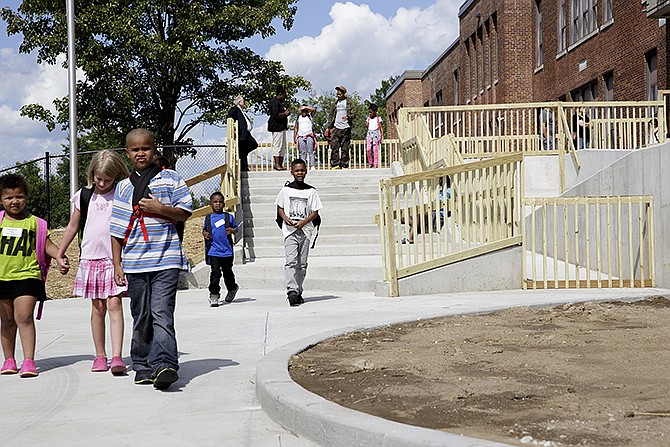Students and parents utilize the newly-built steps and courtyard at East Elementary School Thursday after the first day of school. Wooden handrails were installed as a temporary fix while the administration waits on custom-fitted metal rails, which had to be ordered after the concrete was poured to ensure a perfect fit.