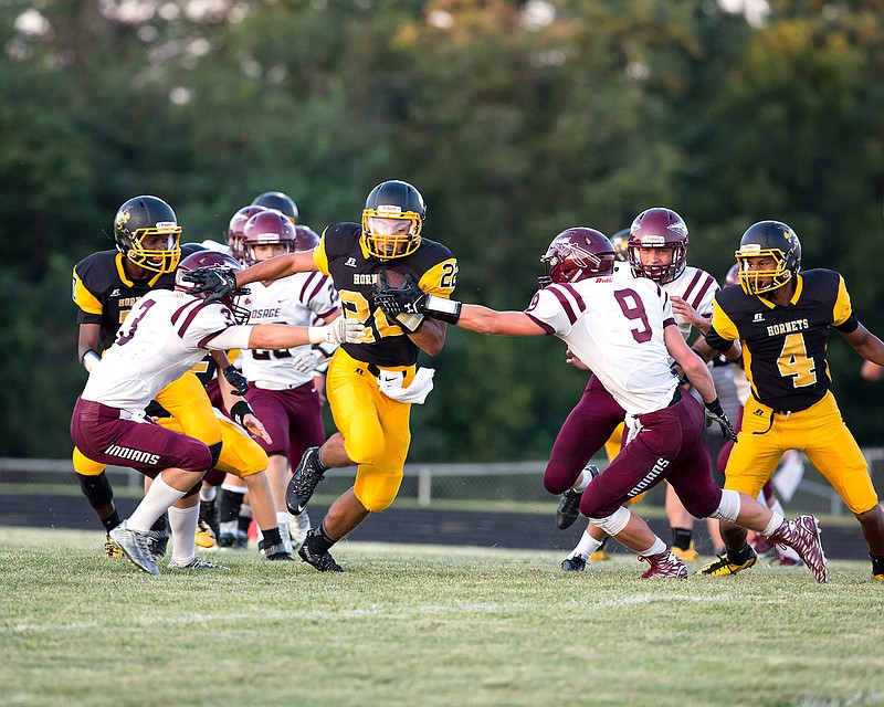 Fulton senior running back Travis Dean gives a stiff-arm to Osage junior linebacker Dylan Riley while slipping through an opening in Friday night's season opener at Robert E. Fisher Jr. Stadium. Dean rushed for a career-high 227 yards and two touchdowns in the Hornets' 33-21 win over the Indians