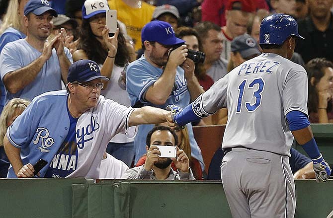 Kansas City Royals' Salvador Perez (13) celebrates his three-run home run with a fan during the sixth inning of a baseball game against the Boston Red Sox in Boston, Saturday, Aug. 22, 2015.