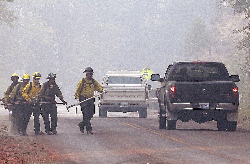 Firefighters walk through heavy smoke in Twisp, Wash. Firefighters across the West saw little relief over the weekend as wildfires raged in the drought-stricken region, but for those in Washington, other states will soon provide additional resources. 
