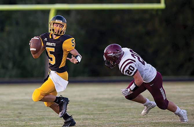 Fulton junior quarterback Devin
Masek tries to elude Osage junior
linebacker Max Drier during the Hornets'
33-21 victory against the Indians
in last Friday's game in Fulton.