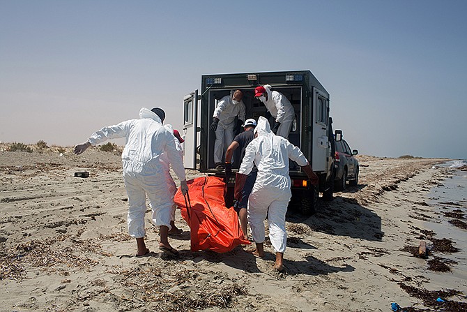 Workers for the Red Crescent carry the body of a dead migrant, in an orange body bag, Friday to a nearby truck, at the waterfront in Zuwara, about 65 miles west of Tripoli, Libya. Two ships went down Thursday off the western Libyan city, where Hussein Asheini of the Red Crescent said more than 100 bodies had been recovered. 
